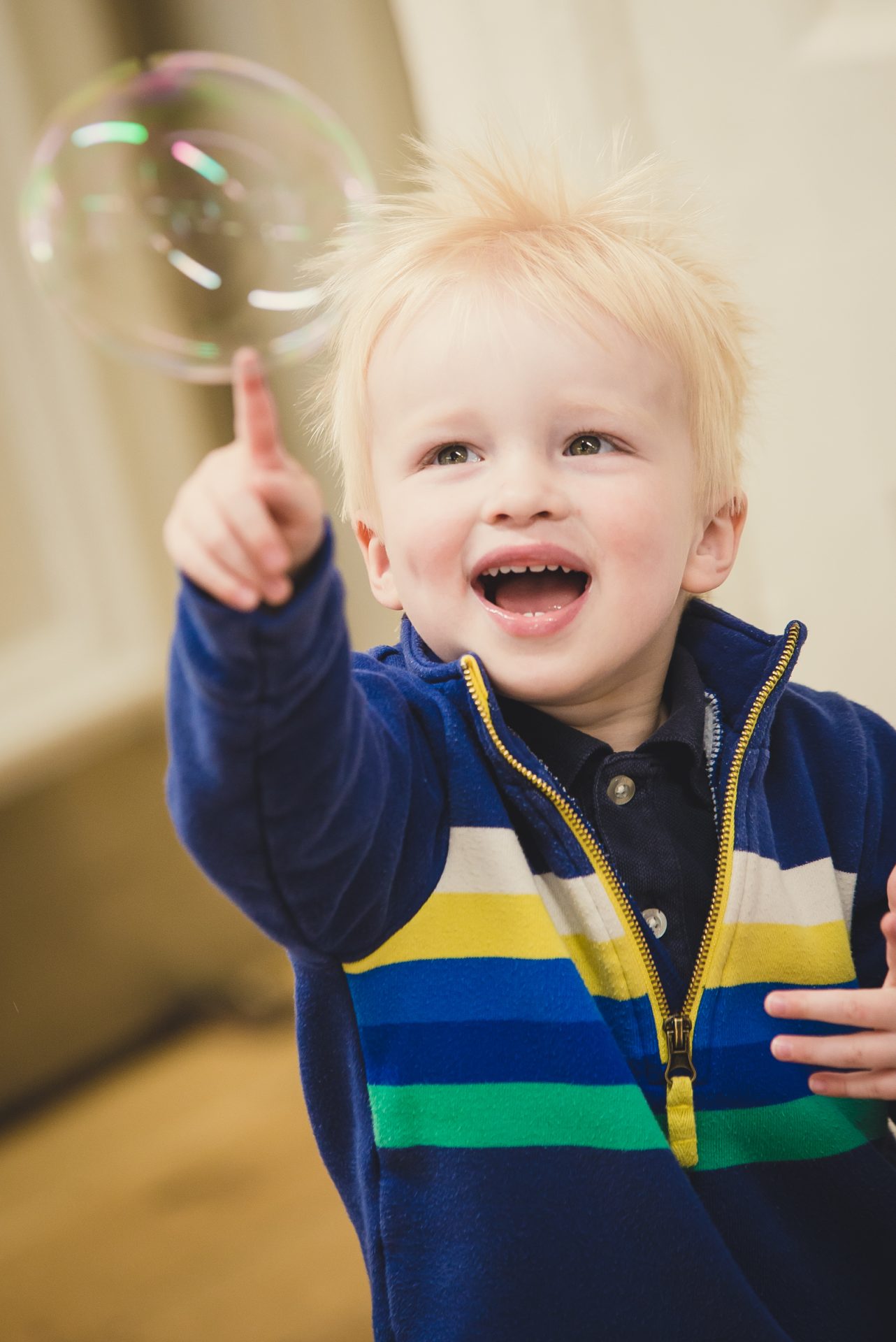 Toddler demonstrates excellent hand eye coordination by popping a bubble with one finger at a Mini Mozart Music Class for babies and toddlers.